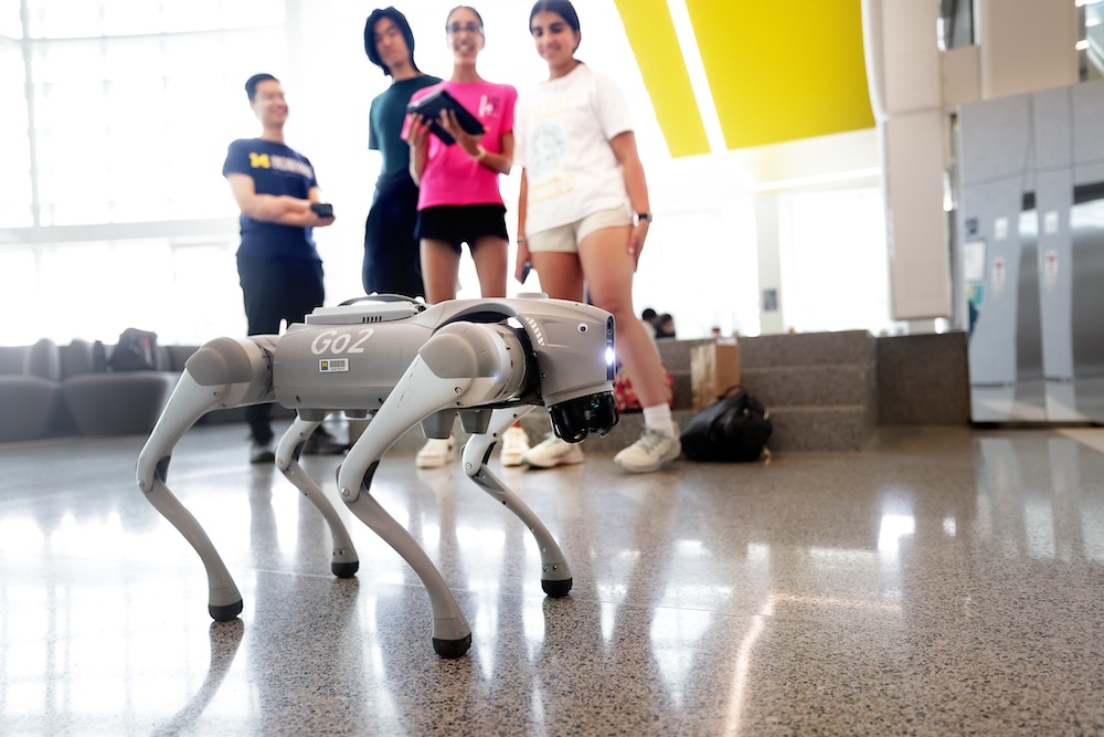 robot dog walks in front of tour of children